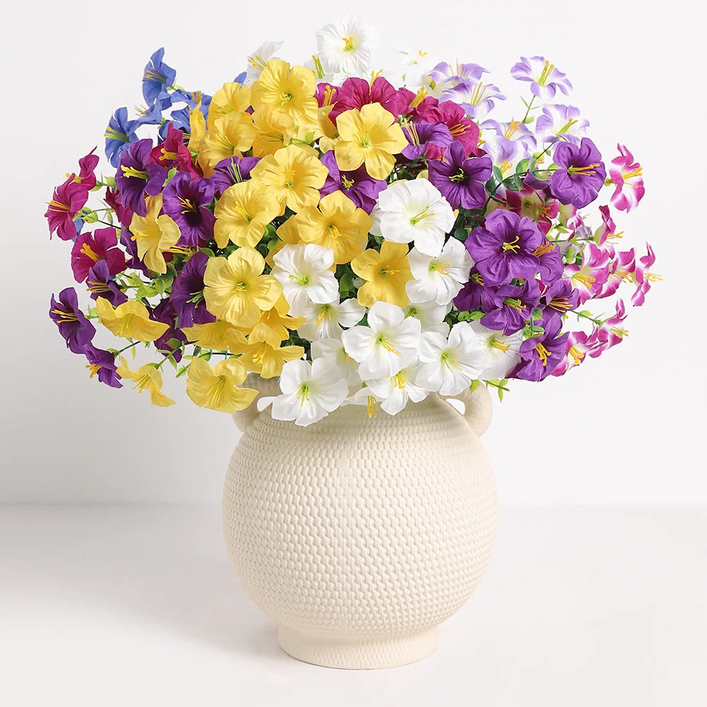 A vibrant bouquet of artificial silk flowers in yellow, purple, and white arranged in a cream-colored vase.