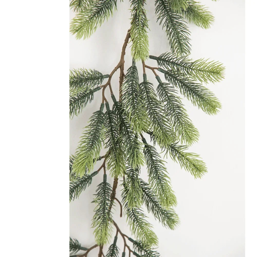 A branch of artificial pine garland with green needles and brown twigs.