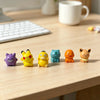 A set of six colorful kawaii anime fantasy creature mini figurines arranged in a row on a wooden desk.