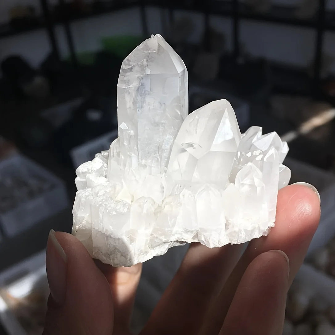 A hand holds a cluster of clear quartz crystals for home decor