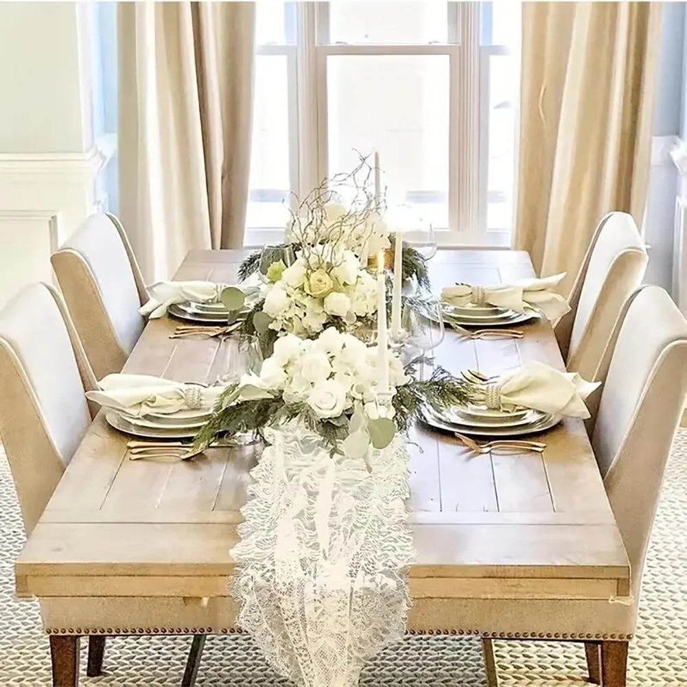 Una rústica mesa de madera con un juego para una comida y arreglos florales blancos y detalles de encaje.