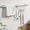 Silver self-adhesive curtain rod holders with various hooks and a wooden hanger mounted on a white wall.