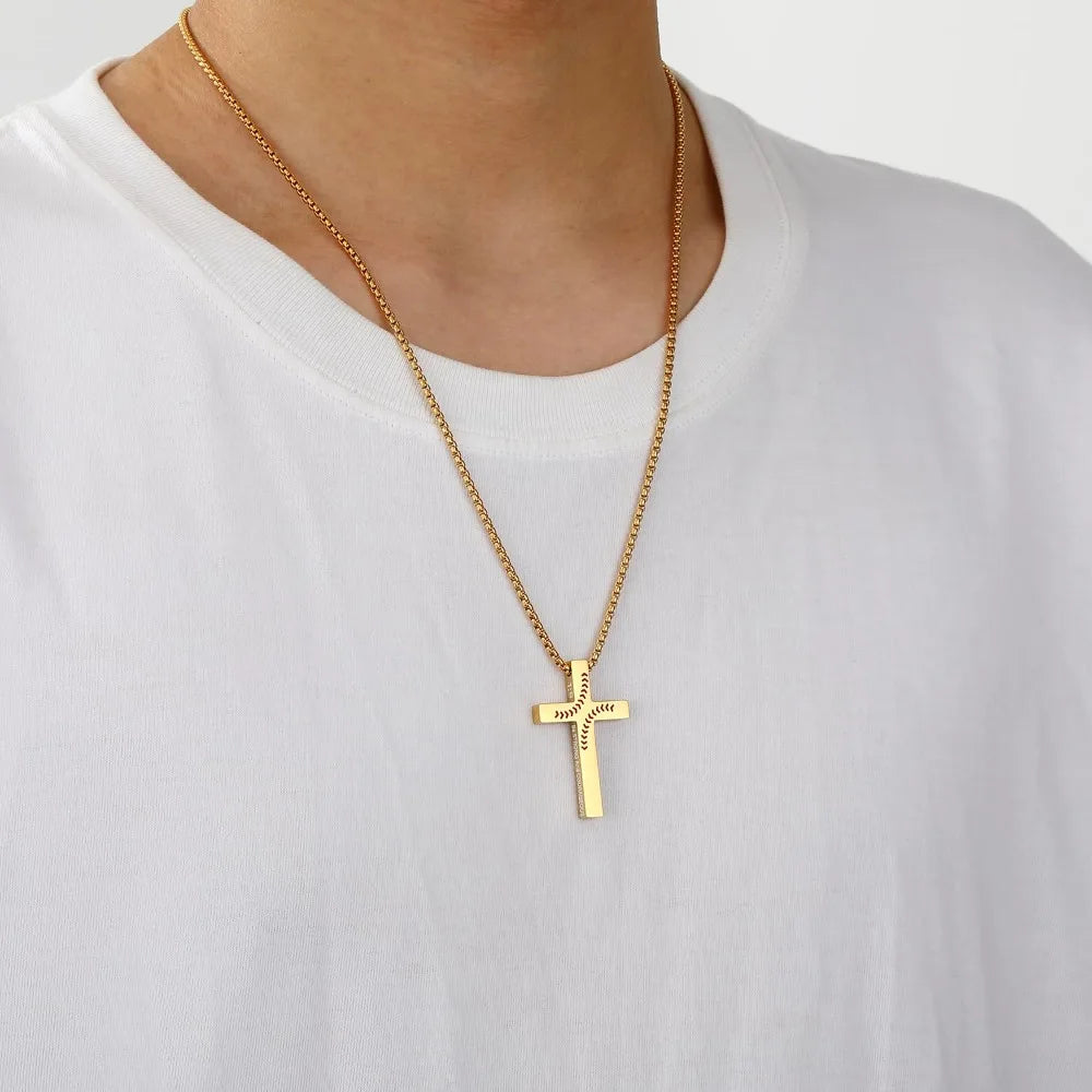 A gold-colored stainless steel cross pendant necklace worn around the neck against a white t-shirt.