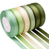A roll of satin silk ribbon in various shades of green and beige, with several strips unwound.