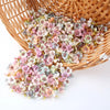 A pile of pink and white silk artificial flower heads in a woven basket for crafts and decor