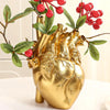 A golden heart-shaped resin vase with green leaves and red berries on a branch.