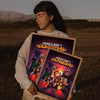 A person holds a framed poster featuring Minecraft dungeons artwork in an outdoor setting.