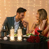 Ein Paar lächelt beim Dekorieren eines Tisches mit Kerzen und Grün für einen Date-Night-Stimmung.