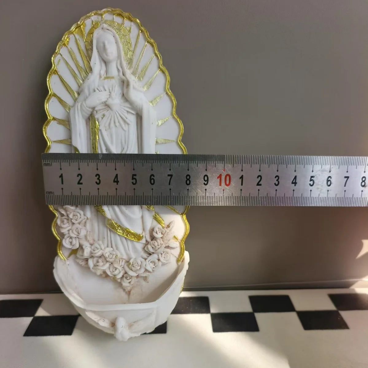 White resin Virgin Mary holy water wall decor statue measured against a ruler.