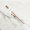 A wooden wand replica with a metal core is displayed on a white marble surface.