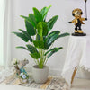 Artificial tropical palm tree with large green monstera leaves potted in a gray ceramic pot