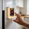 A hand touches a retro NFC music box night light with a rotating disc mounted on a white cabinet door.