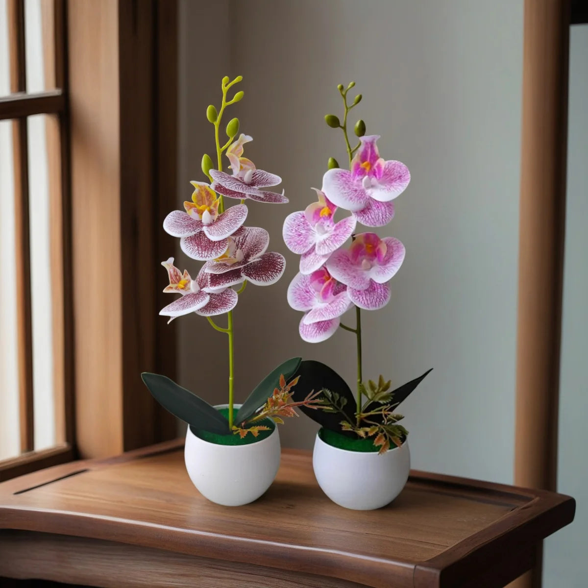 A realistic artificial orchid potted plant with pink and purple flowers displayed on a wooden surface.
