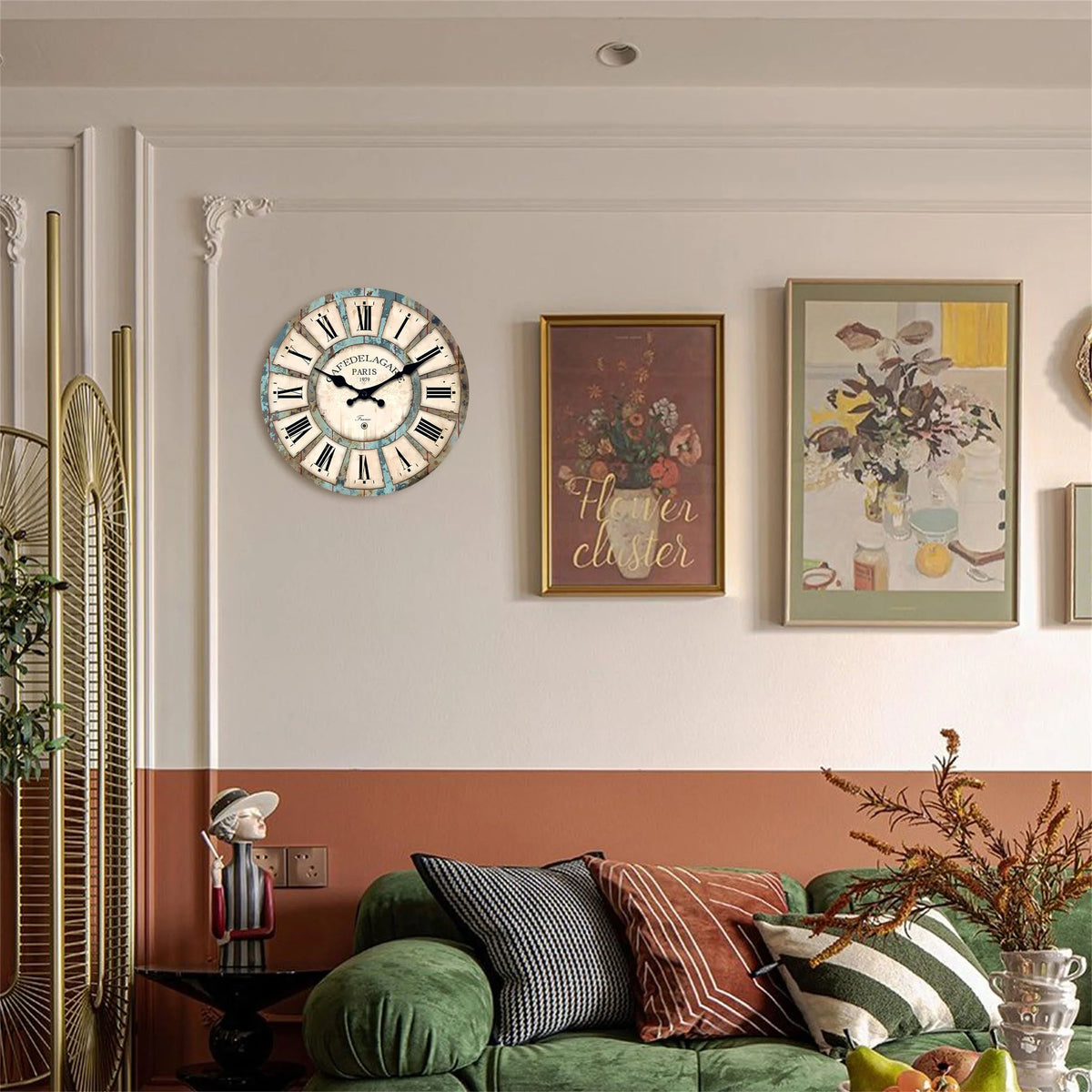A rustic wooden wall clock with a white face and Roman numerals hangs on a light gray wall above a green sofa.
