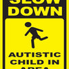 A yellow and black sign warning to slow down for an autistic child in the area.