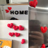 A set of red heart-shaped fridge magnets with the word HOME on a white background.