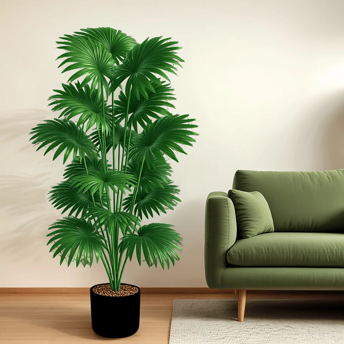 A large artificial palm tree in a black pot standing next to a green sofa and a light rug.