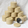 A stack of light wood metal candle tins with lids arranged in a pyramid shape.