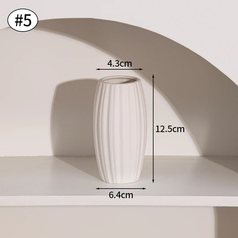 A white, ribbed ceramic vase is displayed on a shelf with a shadow cast by an arched niche.