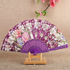 A purple and white floral silk folding fan displayed on a wooden stand.