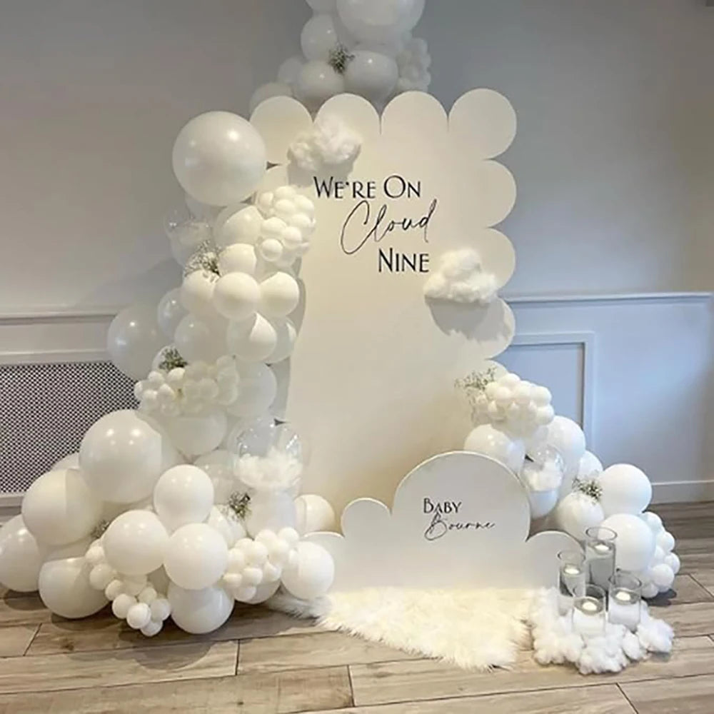 A white balloon arch decoration featuring clouds and balloons for a baby shower or party