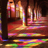 Interior view of an Islamic mosque with arched columns and colorful light patterns cast on the floor.