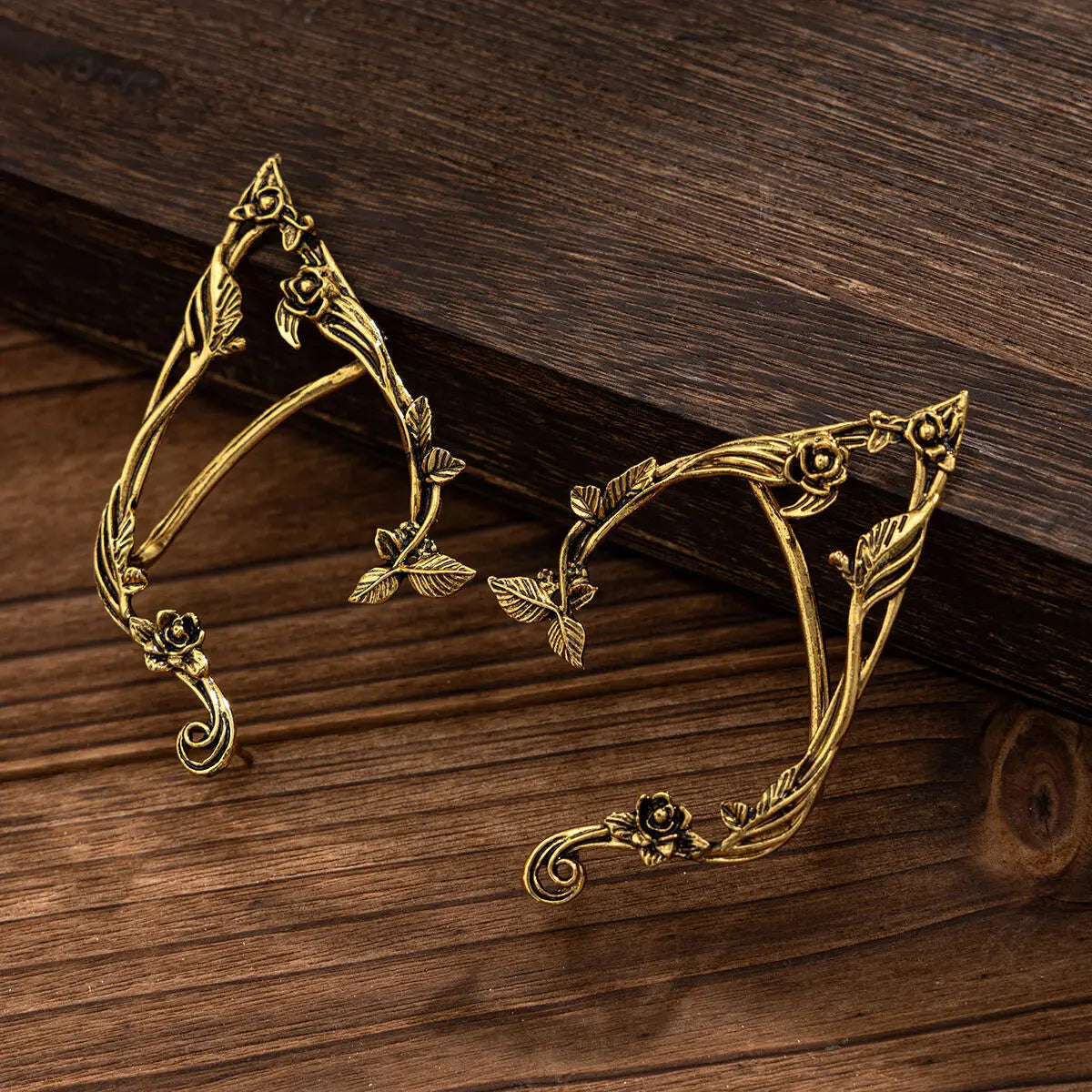 Gold elf flower leaf clip earrings for women displayed on a dark wooden surface