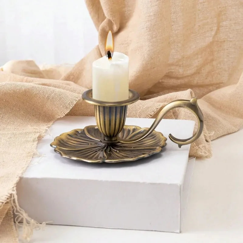 Un photophore en fer forgé vintage avec une bougie blanche, exposé sur un bloc blanc et un tissu en lin beige.