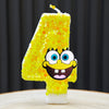 A yellow sponge cake candle shaped like the number 4 with a SpongeBob face design.