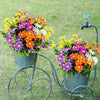 A bouquet of colorful silk daisies in various shades of purple, orange, and yellow displayed in a vintage metal stand.