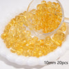 A pile of round, translucent yellow glass spacer beads is shown next to a small glass scoop.