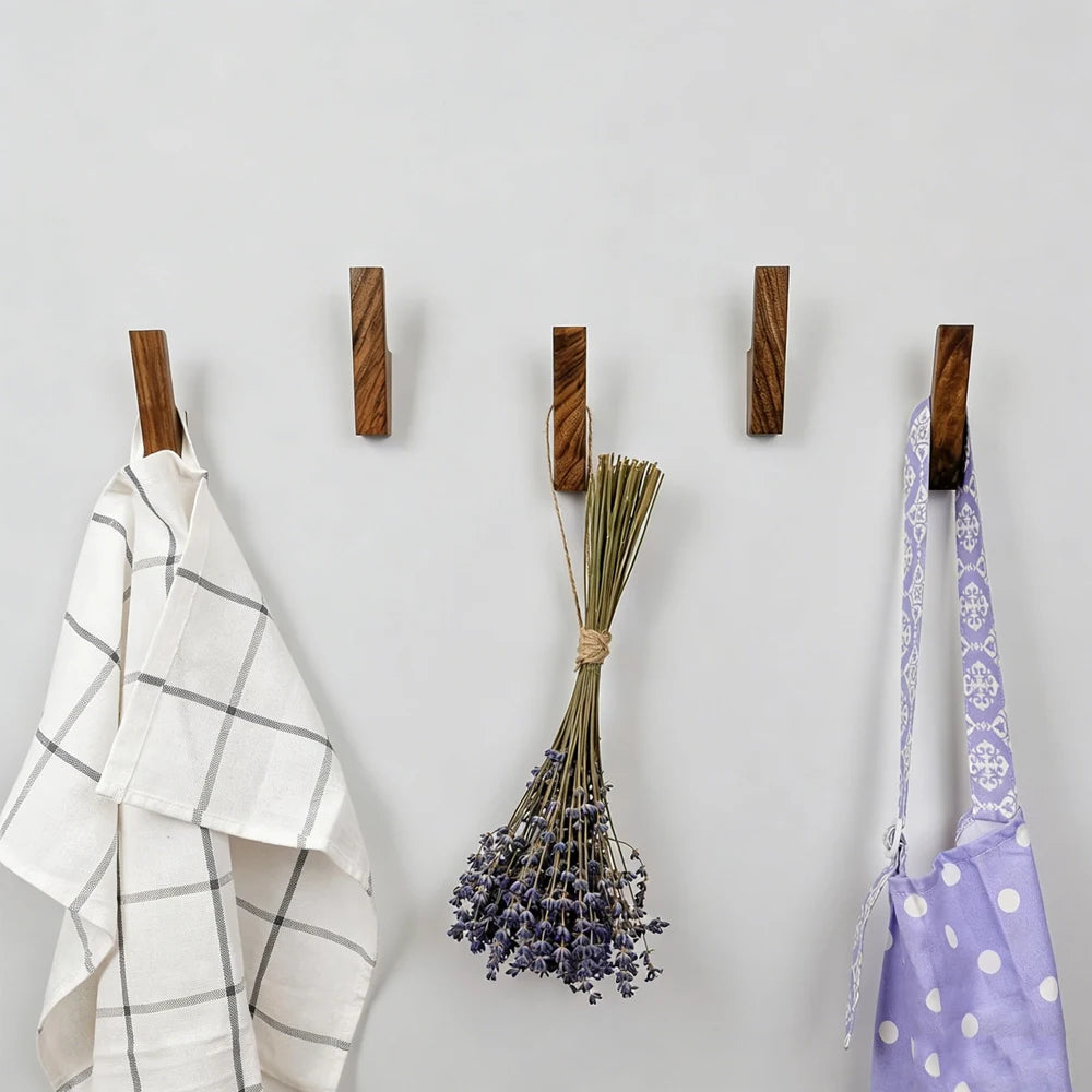 Natürliche Holz-Wandhaken mit Textilien wie einem karierten Handtuch, Lavendel und Stoffriemen.