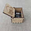 An antique carved wooden music box with a lid displaying the text Beauty and the Beast resting on a woven background.