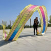 Un artista vestido de negro sostiene un colorido atrezo de danza de dragón arqueándose sobre un área pavimentada bajo un ciel