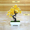 Artificial bonsai tree decoration with yellow blossoms and dark trunk displayed in a white planter.