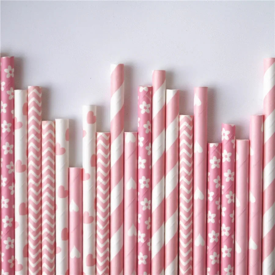 A close-up view of a pack of pink drinking straws featuring white stripes and small pink flowers or hearts.