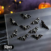A collection of 50 black bat-shaped resin nail charms displayed on a clear surface.