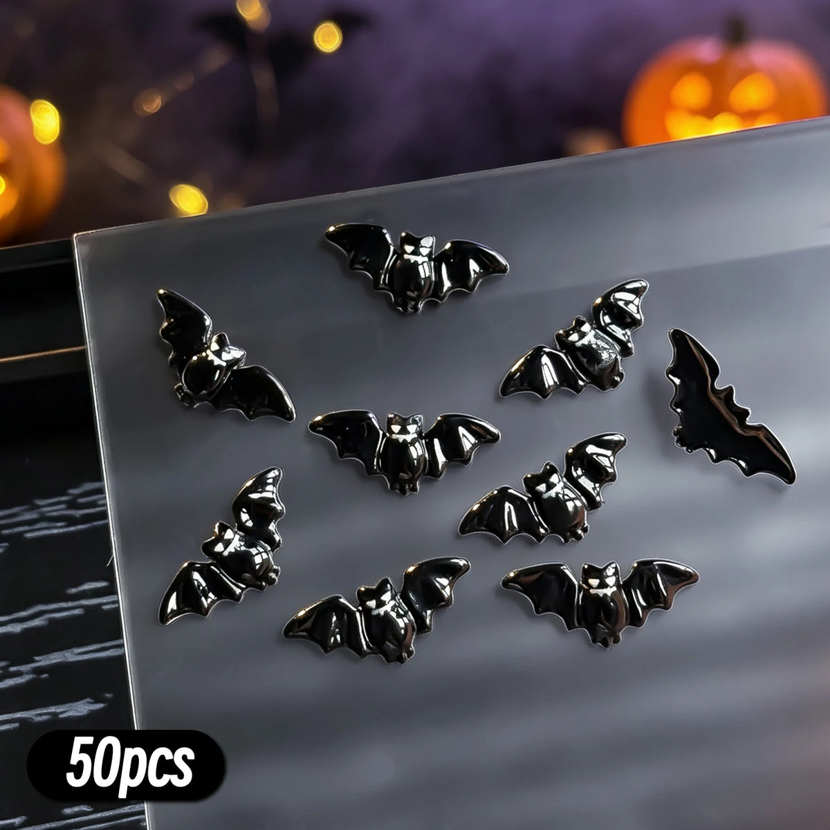 A collection of 50 black bat-shaped resin nail charms displayed on a clear surface.