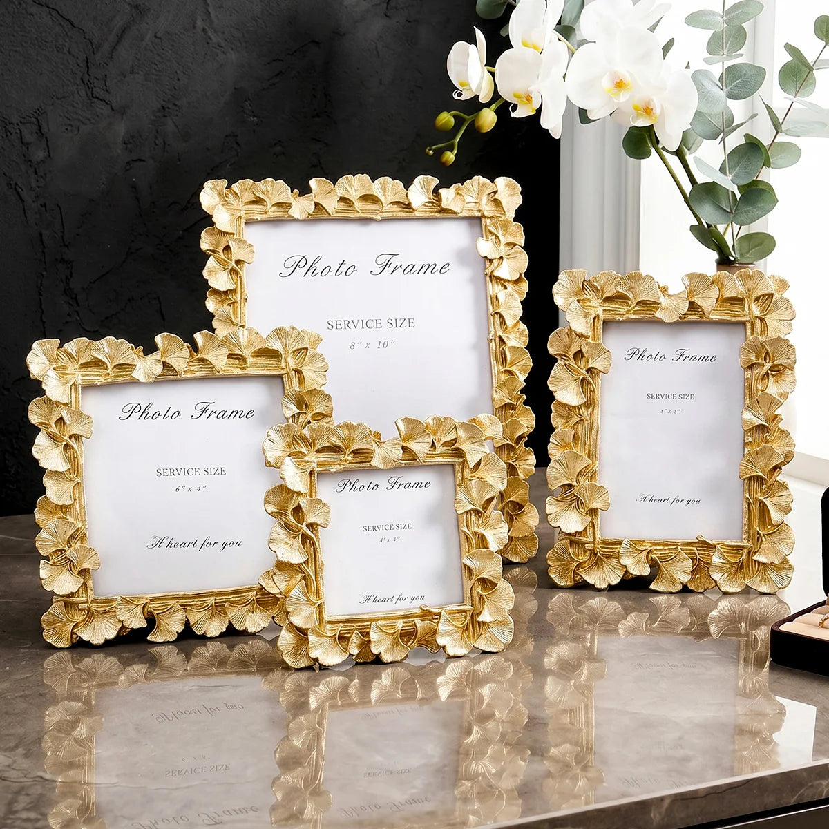 Gold-framed photo frames with white mats and a heart for you message displayed on a marble surface