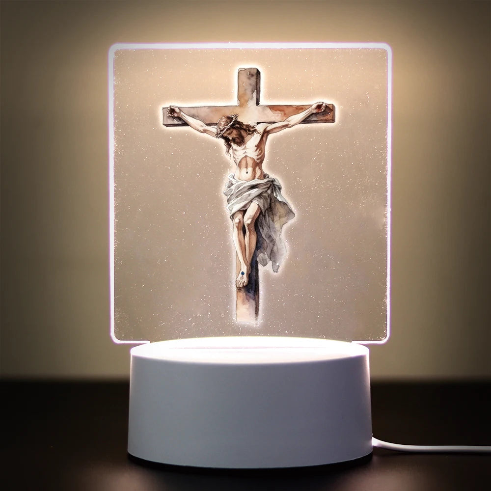 A 3D LED night light displays a crucifix with a figure of Jesus on a light background.