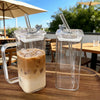 A glass coffee mug filled with iced latte on a wooden table outdoors