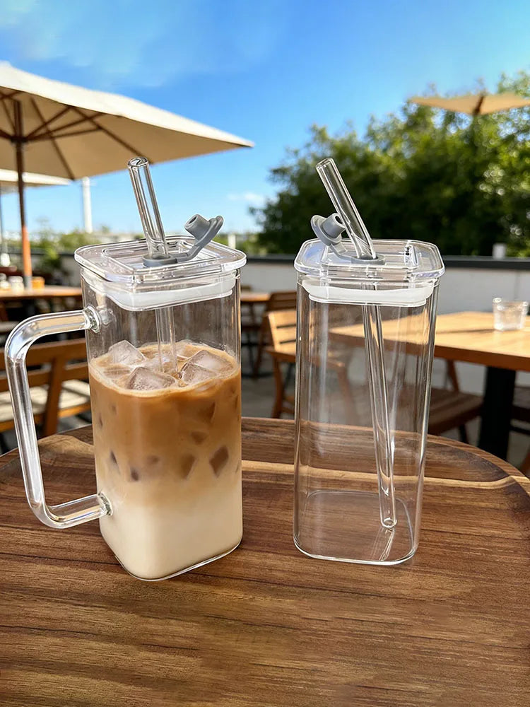 A glass coffee mug filled with iced latte on a wooden table outdoors