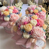 A bouquet of pink and cream floral silicone candle molds shaped like roses, peonies, and camellias.