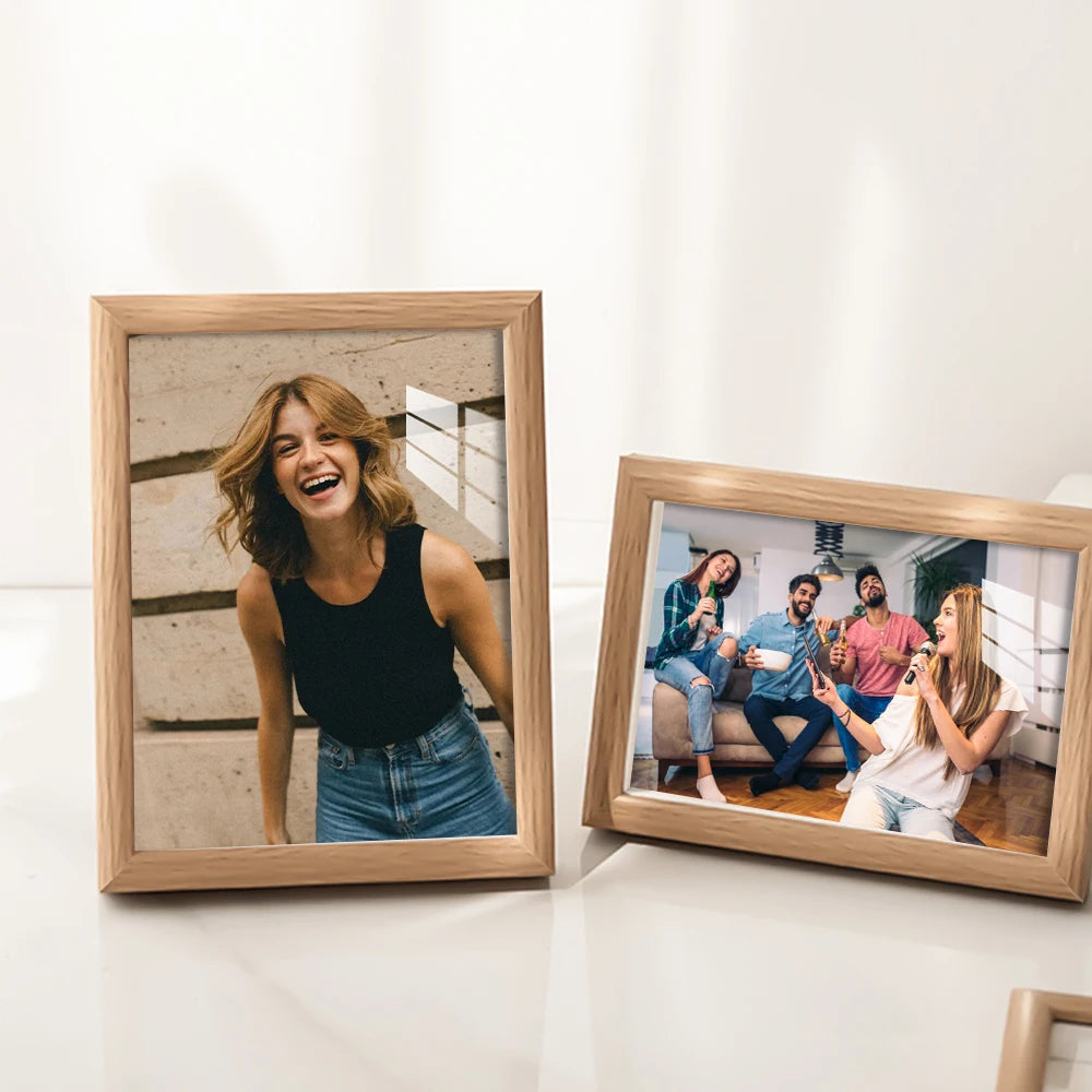 A wooden photo frame displaying a smiling young woman, with another framed photo of friends.