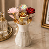 A bouquet of iridescent gold foil roses in various shades of pink and red displayed in a white woven vase.