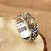 A close-up of a gold and silver Feng Shui Pixiu ring featuring a dragon head design on a wooden surface.