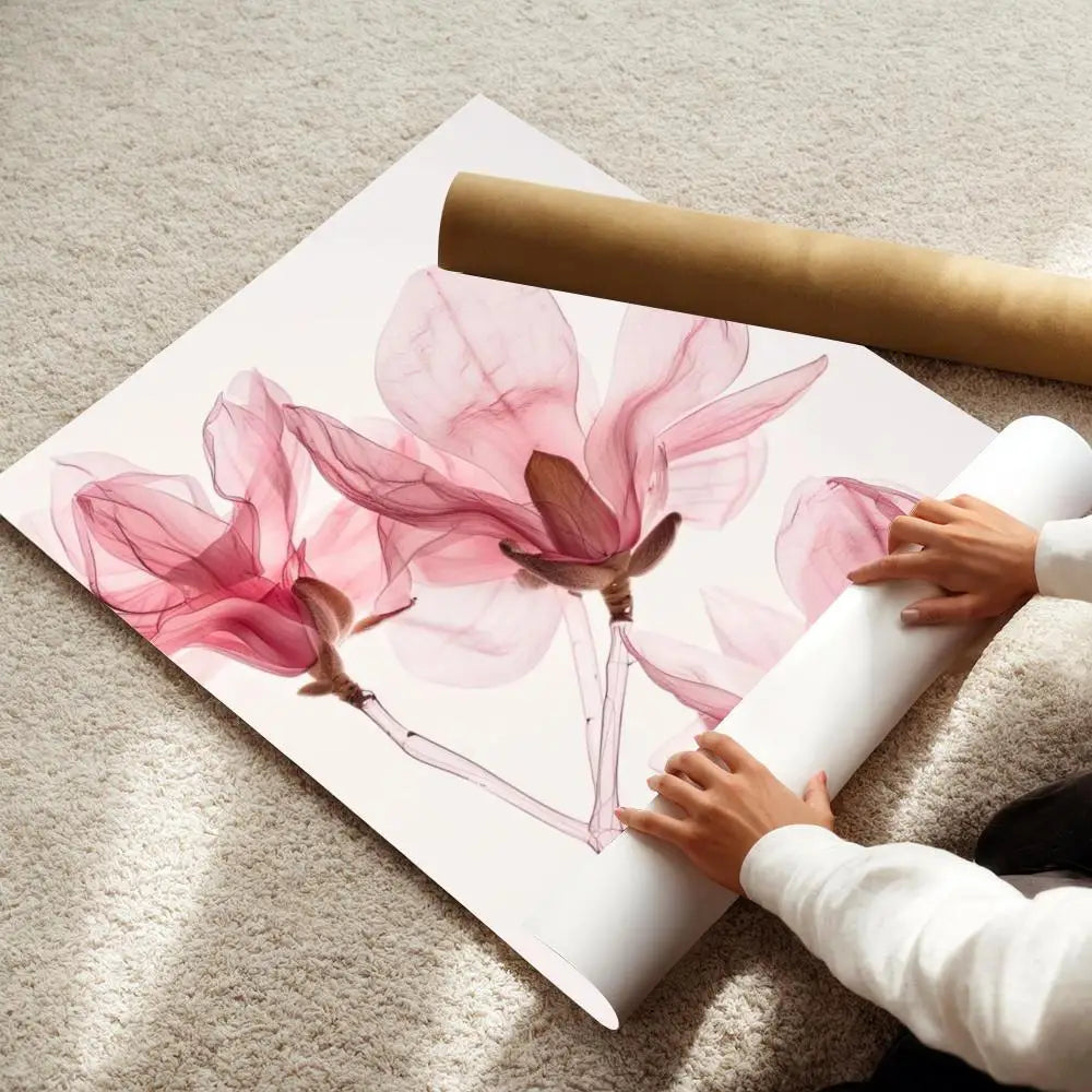 A watercolor illustration of pink and magenta lotus flowers on a white poster, next to a rolled canvas.