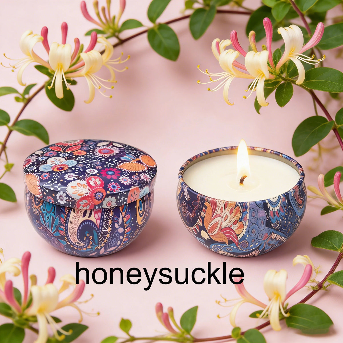 A jar of soy wax candle with a floral pattern sits next to its lid on a pink background surrounded by greenery and flowers.