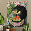A tapestry featuring a black cat sitting on a bowl filled with goldfish, set against a floral background.