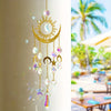 A golden sun and crescent moon wind chime with dangling crystal charms hanging on a white pillar.